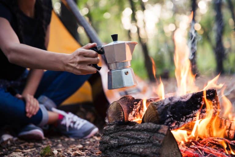 Couple making coffee on the bonfire with a percolator