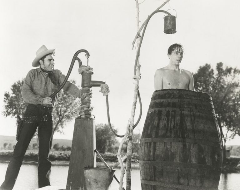 cowboy taking a shower outdoors in a barrel