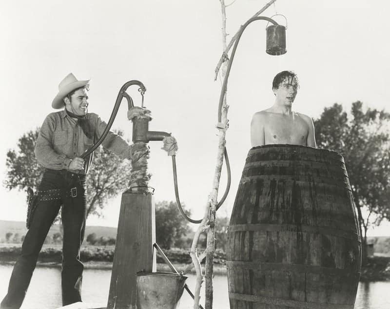 cowboy taking a shower outdoors in a barrel
