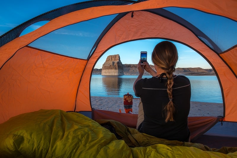 girl camping using a phone in her tent