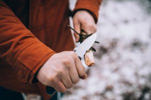 man cutting a stick with a knife outdoors
