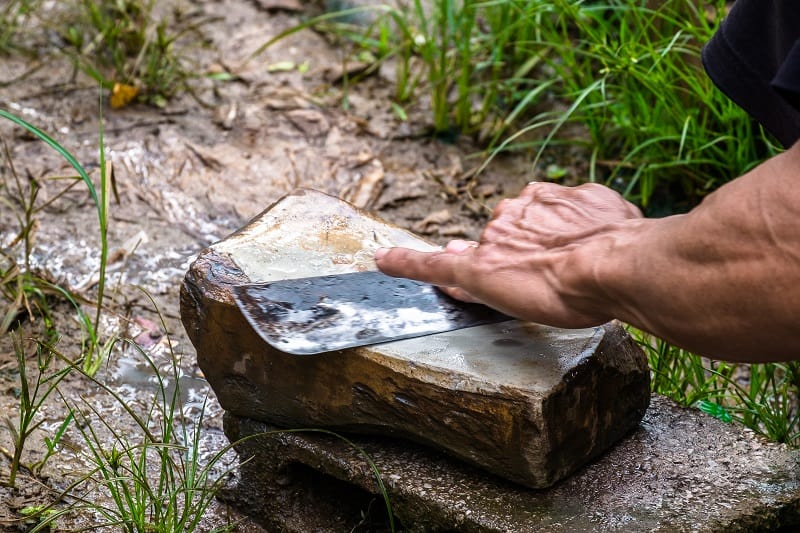 man sharpening a knife with whetstone